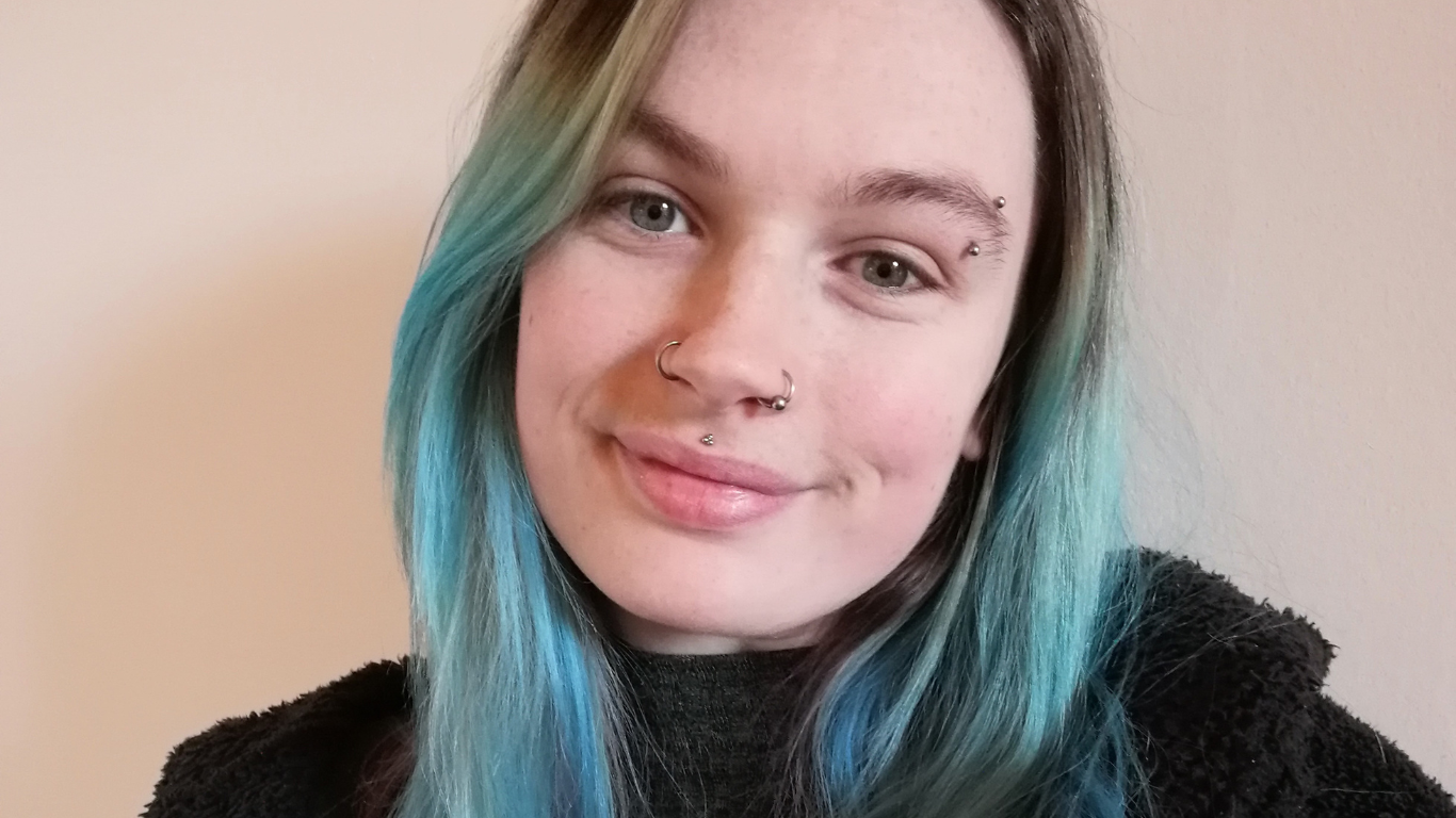 image shows frankee smiling to camera wearing a black jumper and fabulous blue hair