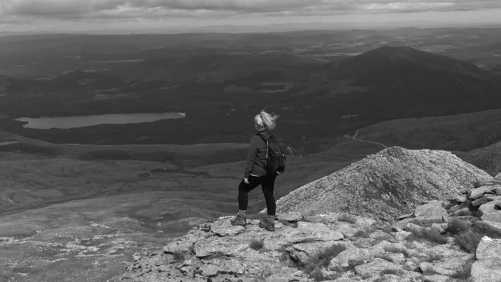 Black and white image shows Danni-Jo looking over the horizon after conquering Ben Nevis.
