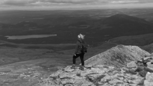 Black and white image shows Danni-Jo looking over the horizon after conquering Ben Nevis.